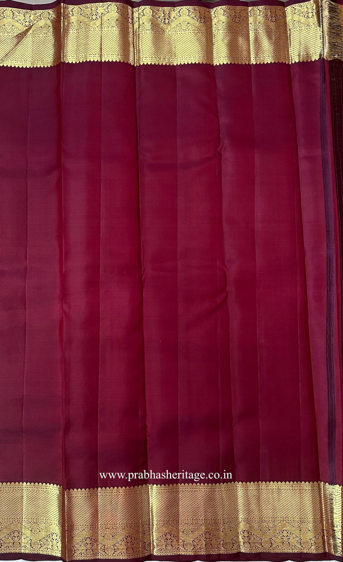Matching wine-coloured blouse piece with a gold zari peacock border
