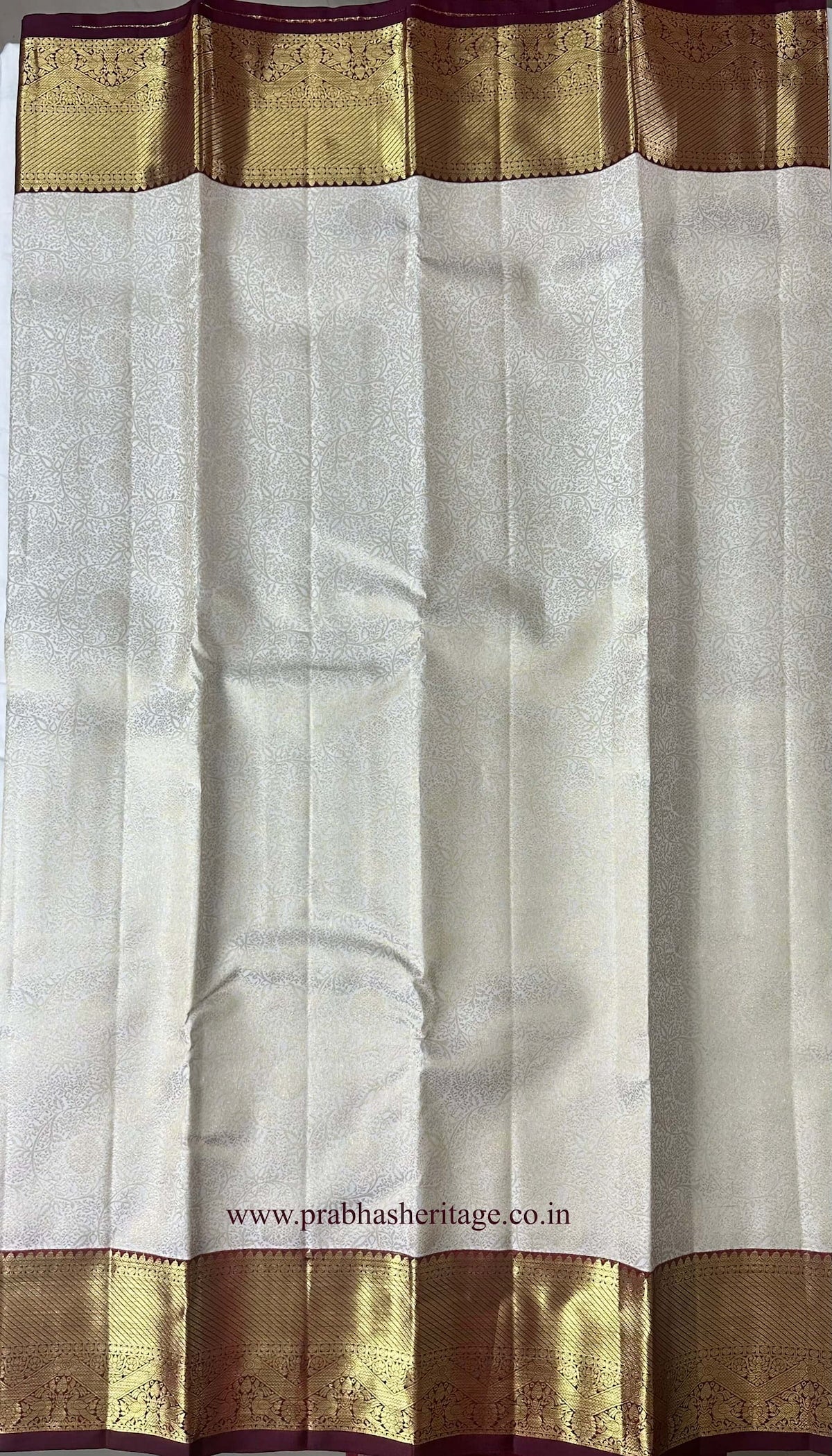 Brocade-style floral medallion pattern on the ivory silk body of the saree