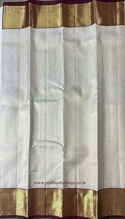 Brocade-style floral medallion pattern on the ivory silk body of the saree