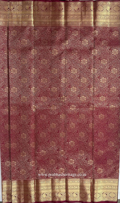 Dense gold zari floral lattice on the deep magenta silk body of the saree