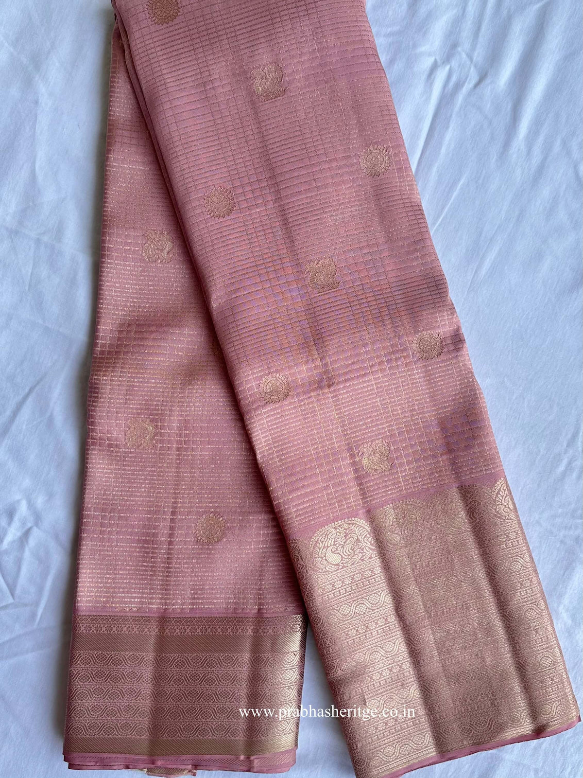Hamsanandi Swarna Naadam – full saree in long fold showing mauve pink body with fine zari grid, ornamental buttas and broad gold zari border.