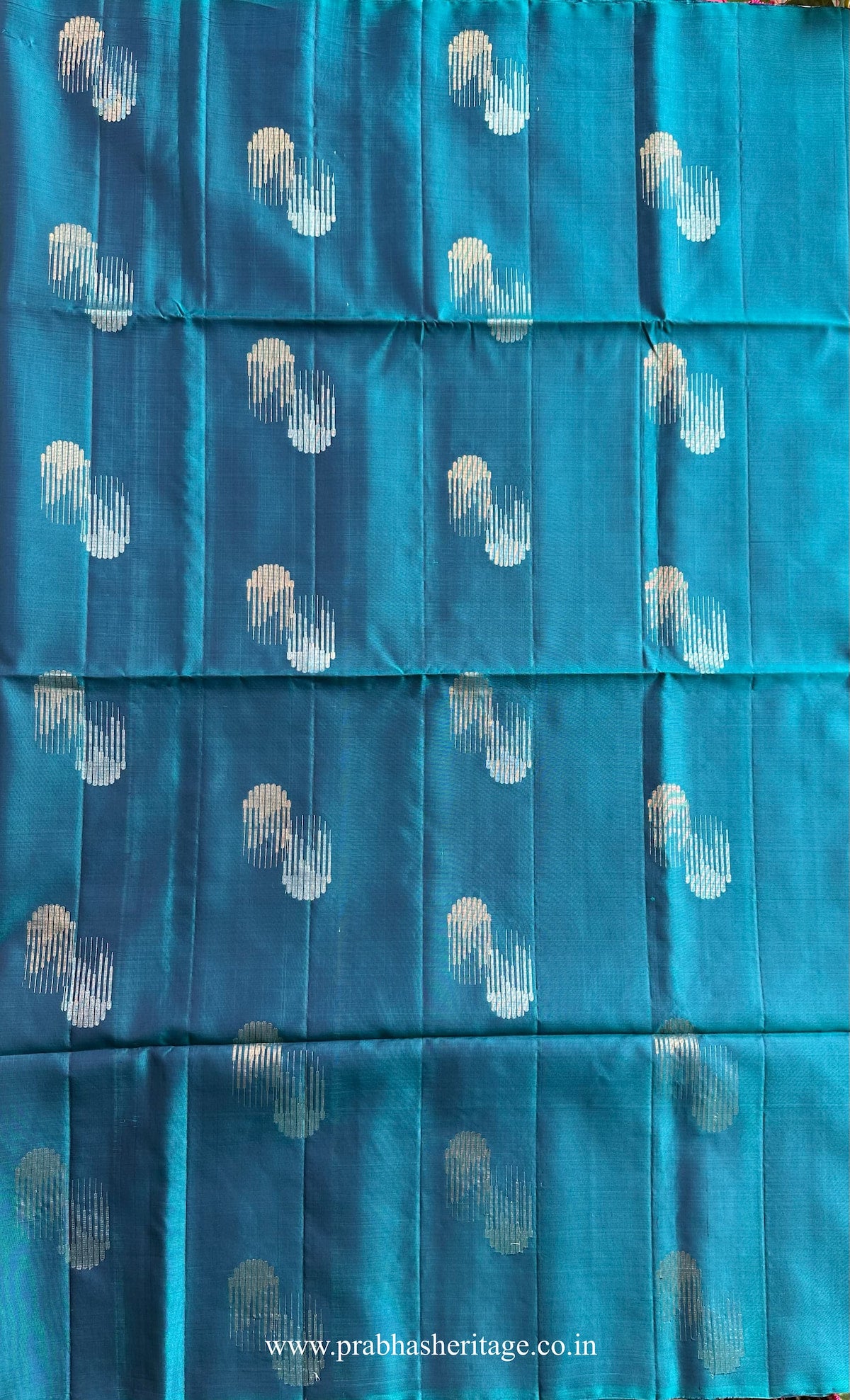 Abstract dual-toned zari buttas on the peacock blue silk body