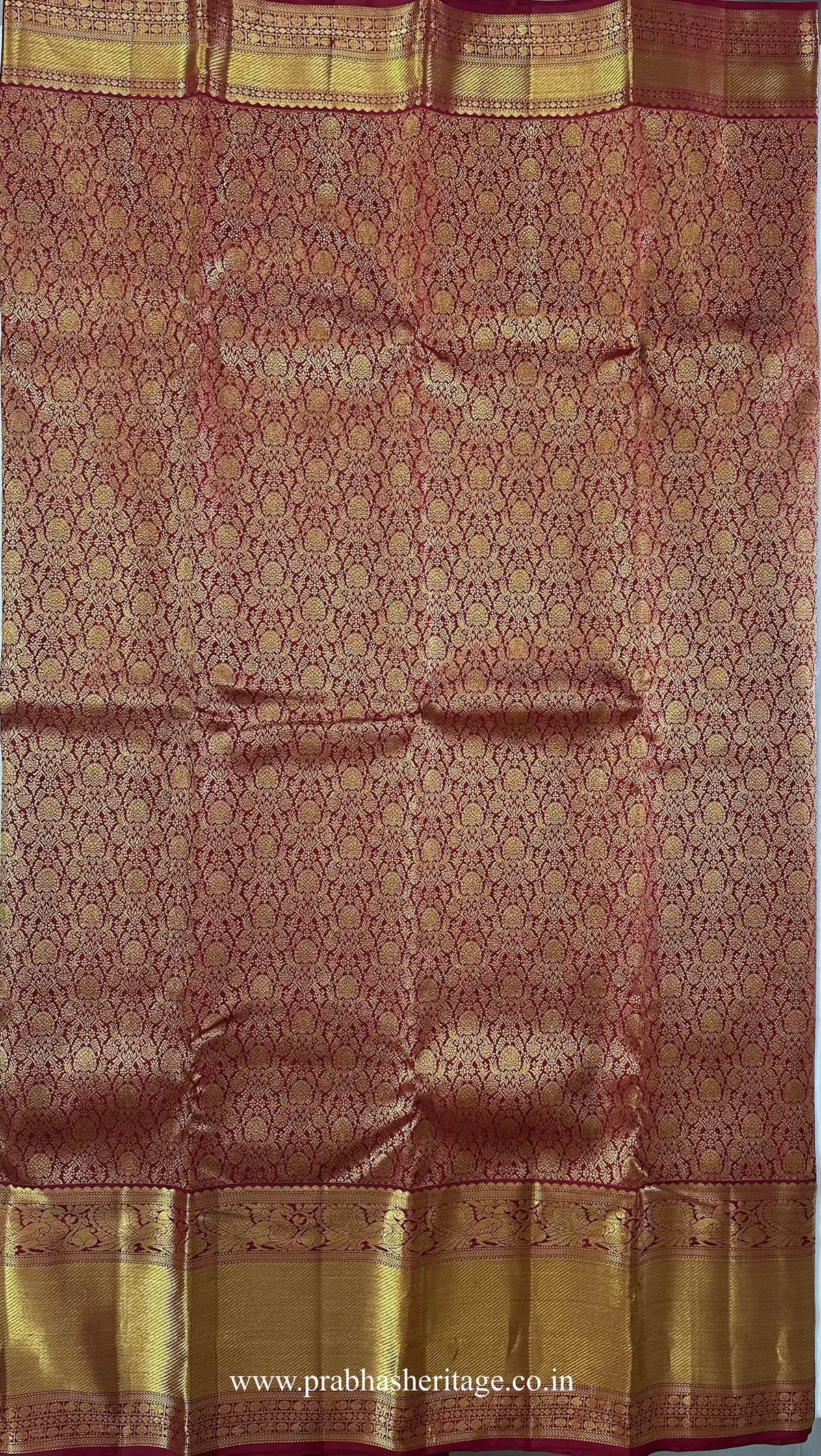 Dense floral zari brocade across the crimson-red silk body of the saree