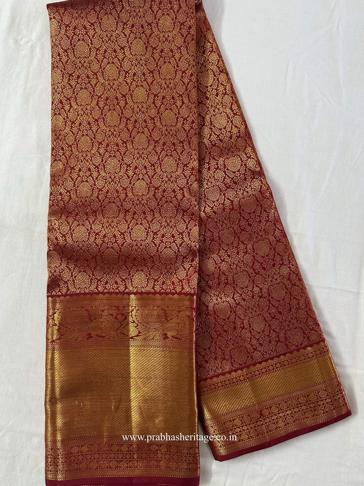 Full length of the crimson-red Kanchipuram silk saree with its asymmetric zari border