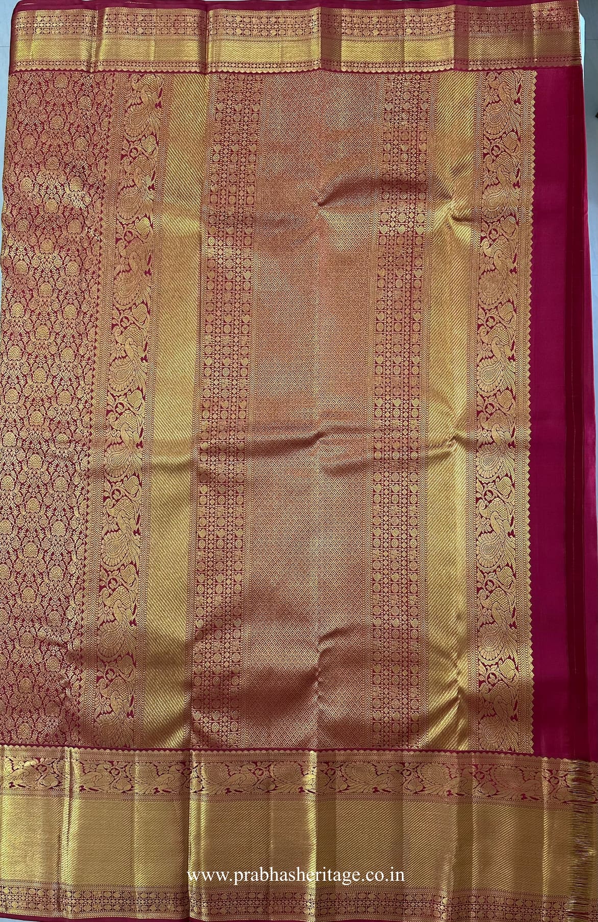 Pallu with peacock motifs and geometric zari panels on the crimson-red silk saree