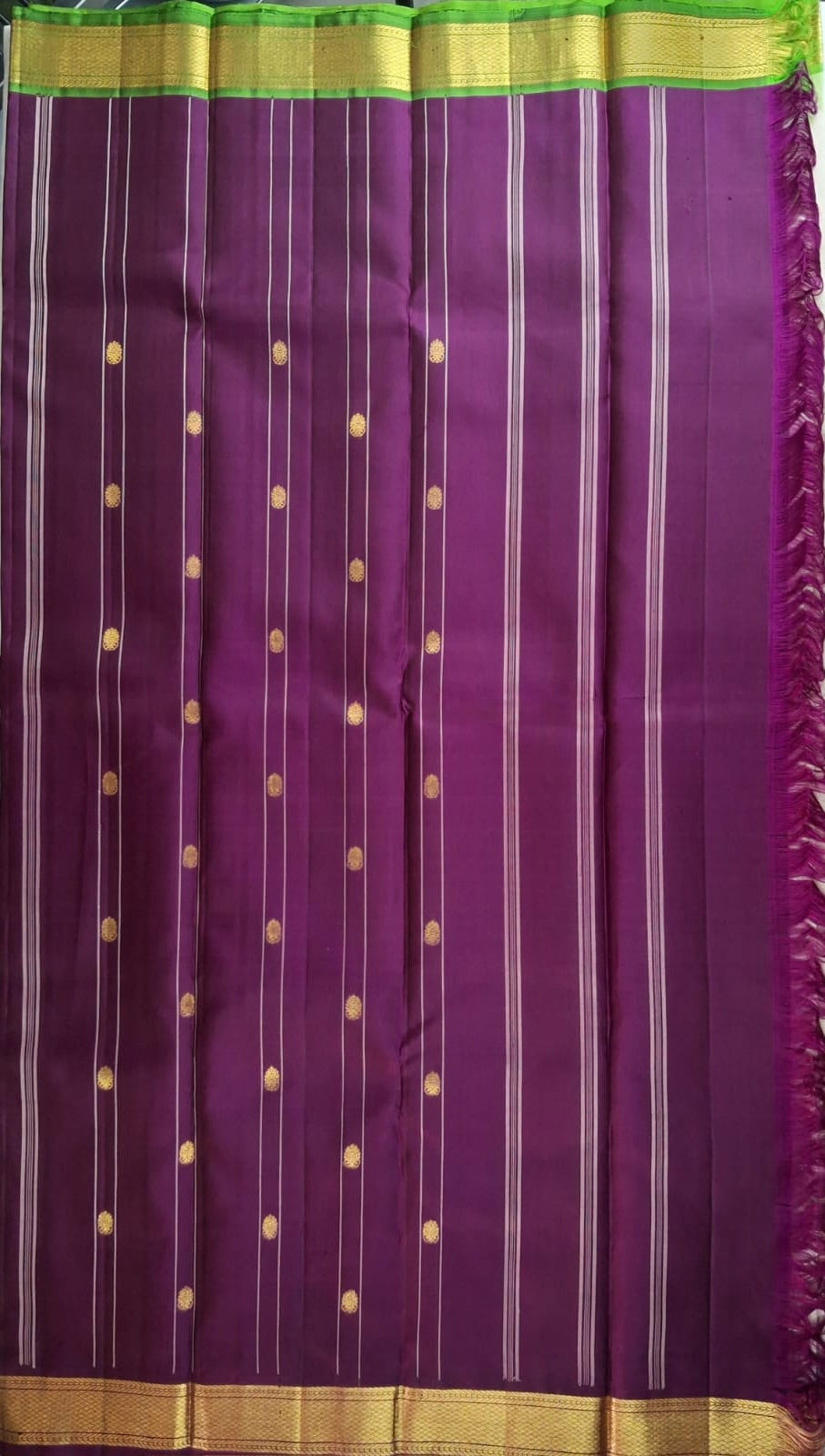Burgundy and leaf green pallu worked in gold zari on an ivory Kanchipuram silk saree