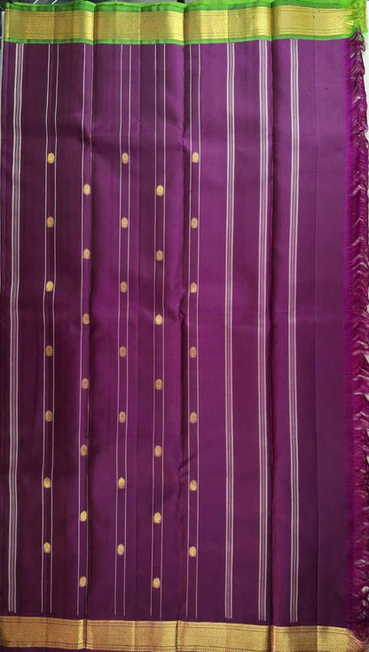 Burgundy and leaf green pallu worked in gold zari on an ivory Kanchipuram silk saree