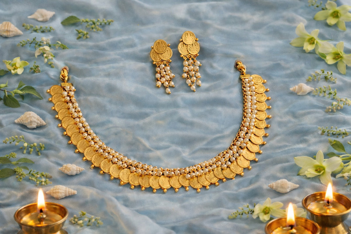 Lakshmi coin temple necklace set with pearl-like bead detailing and matching coin earrings, arranged on blue satin.