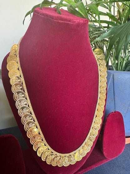 Lakshmi Haram Kasu Mala displayed on a maroon jewellery mannequin, showing the full-length traditional gold-tone coin design.