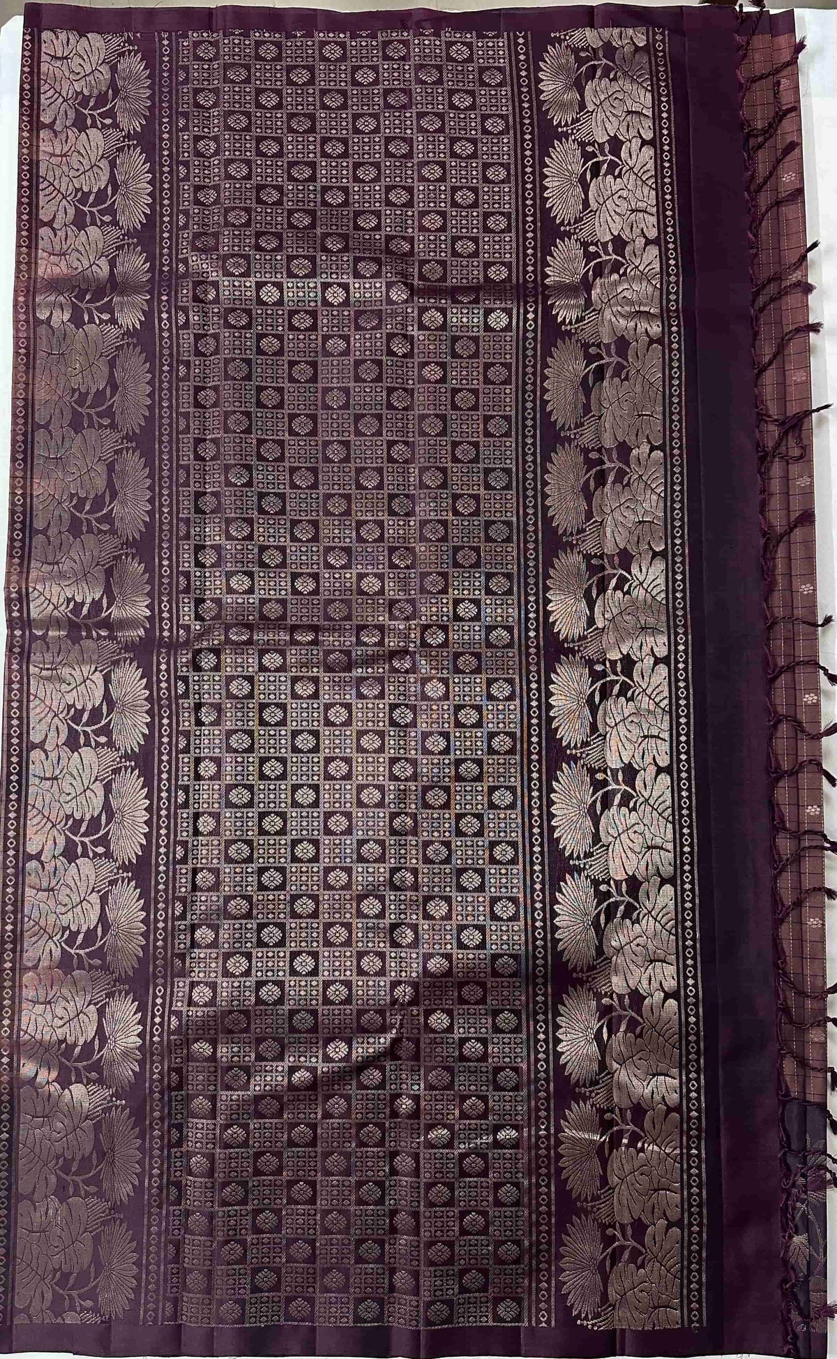 Deep aubergine-plum pallu with geometric patterning and broad floral bands on a pure soft silk saree