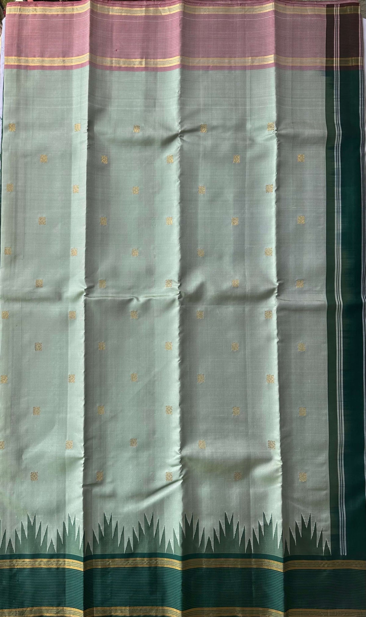 Gold zari buttas on the muted ivory sage silk body of the Shaanta Varnam saree