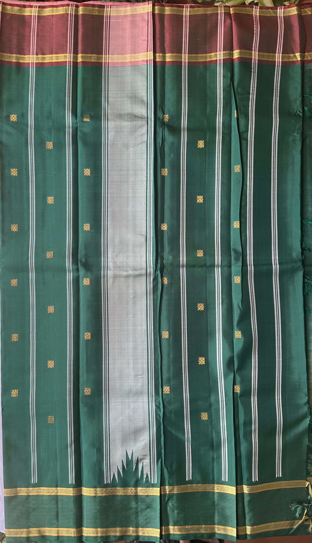 Emerald green and rose-mauve pallu worked in gold zari on an ivory sage silk saree