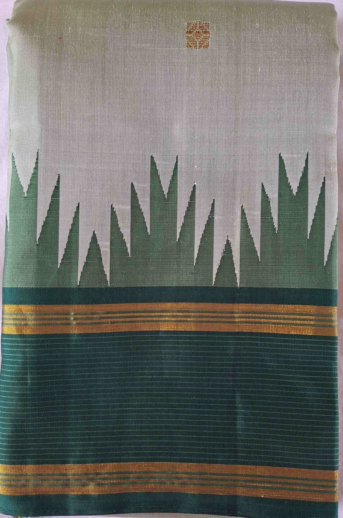Ivory sage Kanchipuram silk saree folded to show the body and emerald green border