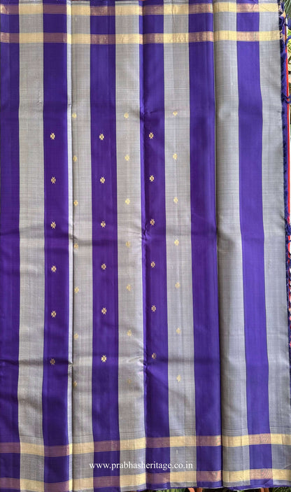 Striped pallu in violet and silver-grey panels with zari motifs on a vermilion-orange silk saree