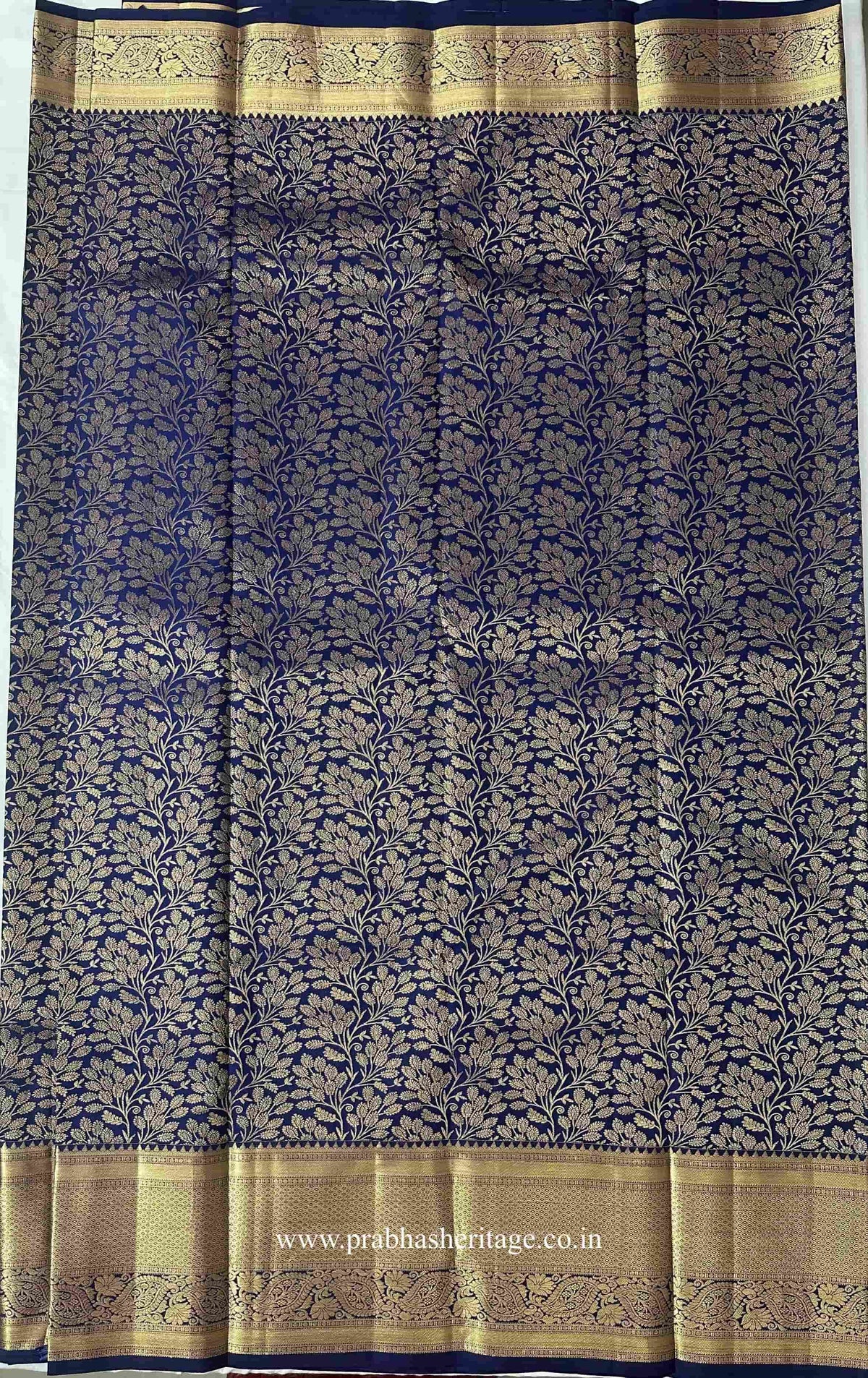 All-over gold zari botanical vine pattern on the navy-blue silk body of the saree