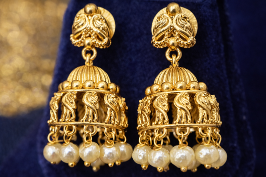 Close-up of matching temple Jhimikki earrings with peacock motifs and pearl drops from the Lakshmi Kasu necklace set