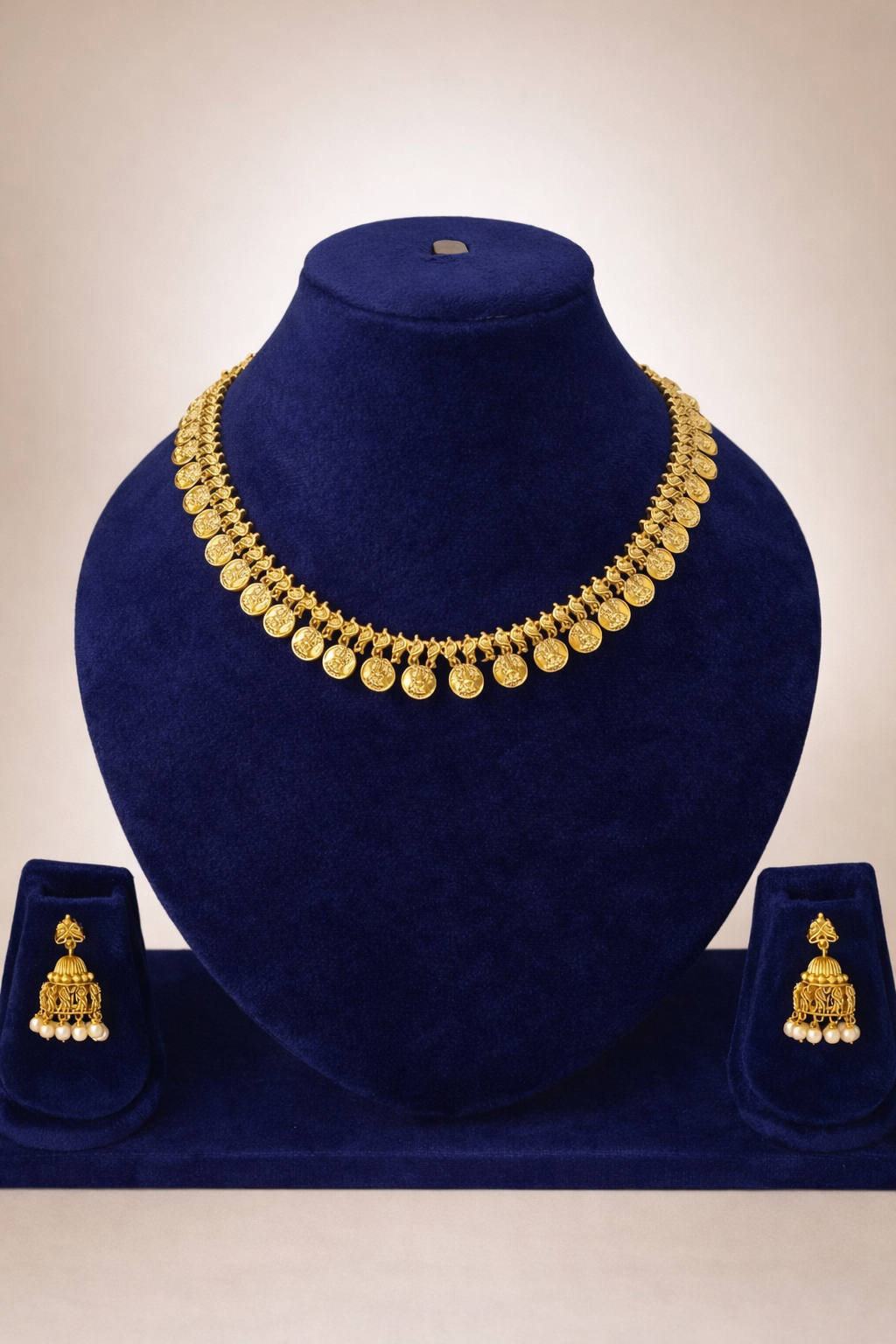 Lakshmi Kasu temple necklace with matching Jhimikki earrings displayed on a blue velvet jewellery mannequin.